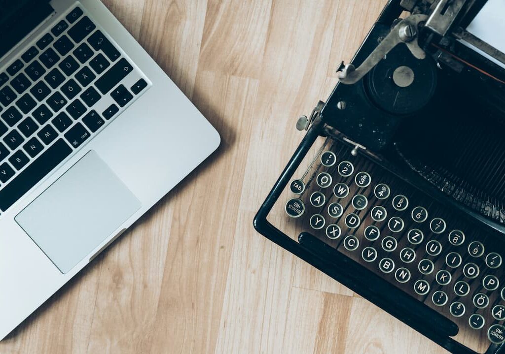 comparison of a typewriter and laptop on a table