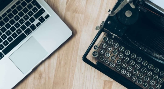 comparison of a typewriter and laptop on a table